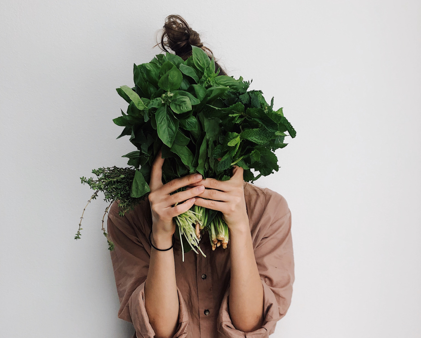 Kobieta trzymajÄ…ca zielenine w dÅ‚oniach przed twarzÄ…